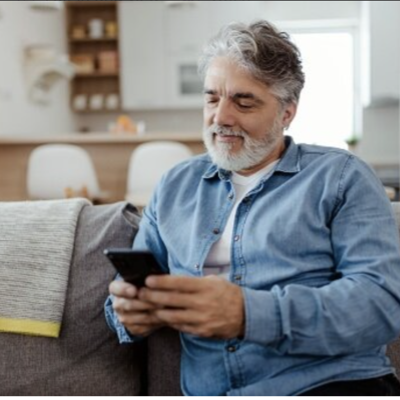 A happy person using their smart phone in their living room.
