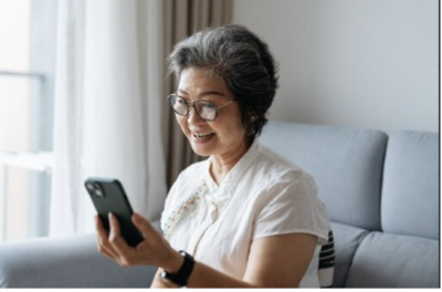 A happy person using their smart phone in their living room.